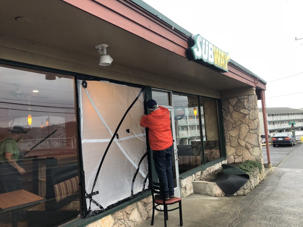 Mayor Don Williams tapes plastic to cover the hole left by an act of vandalism